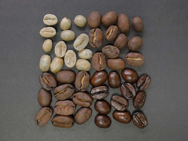 Different roasts of coffee beans make a square shape on a flat surface. The square is divided into 4 smaller squares, the top left is the light roasted coffee beans, the top right is the medium roasts, the lower right is the dark roasts and the lower left is the medium dark roasts.