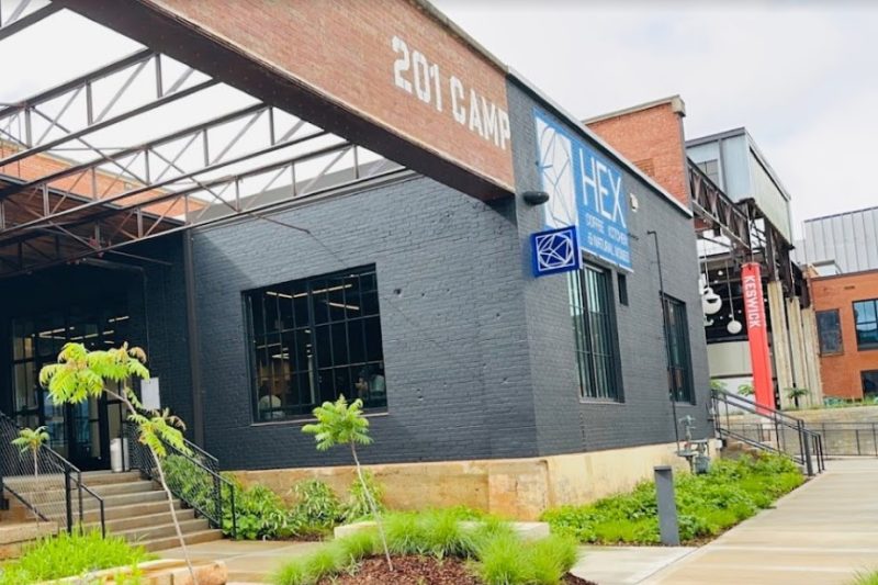 Hex Coffee Kitchen & Natural Wine Store Front. The brick building is painted over with dark gray with a few external walls are strategically bare, without the paint, exposing the original brick texture with fading reddish orange color. It is one of the most popular coffee shops in Charlotte NC.